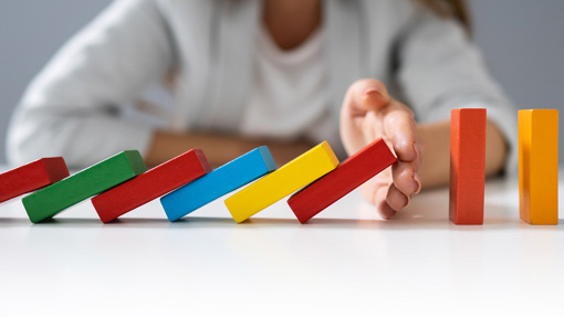 Person stops domino chain with hand