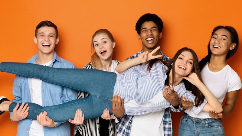 Four teens standing in a line holding fifth teen up in their arms.